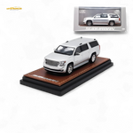 Model of a white SUV on a brown leather stand with a display case in the background.
