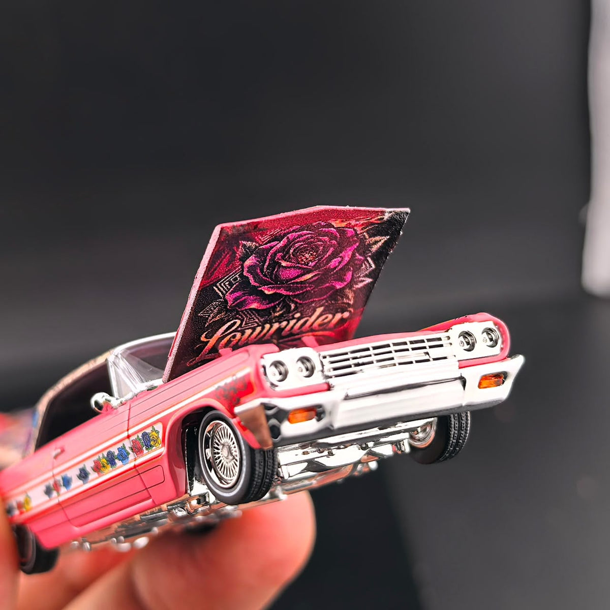Close-up of the Impala hood raised with rose Lowrider artwork and chrome grille
