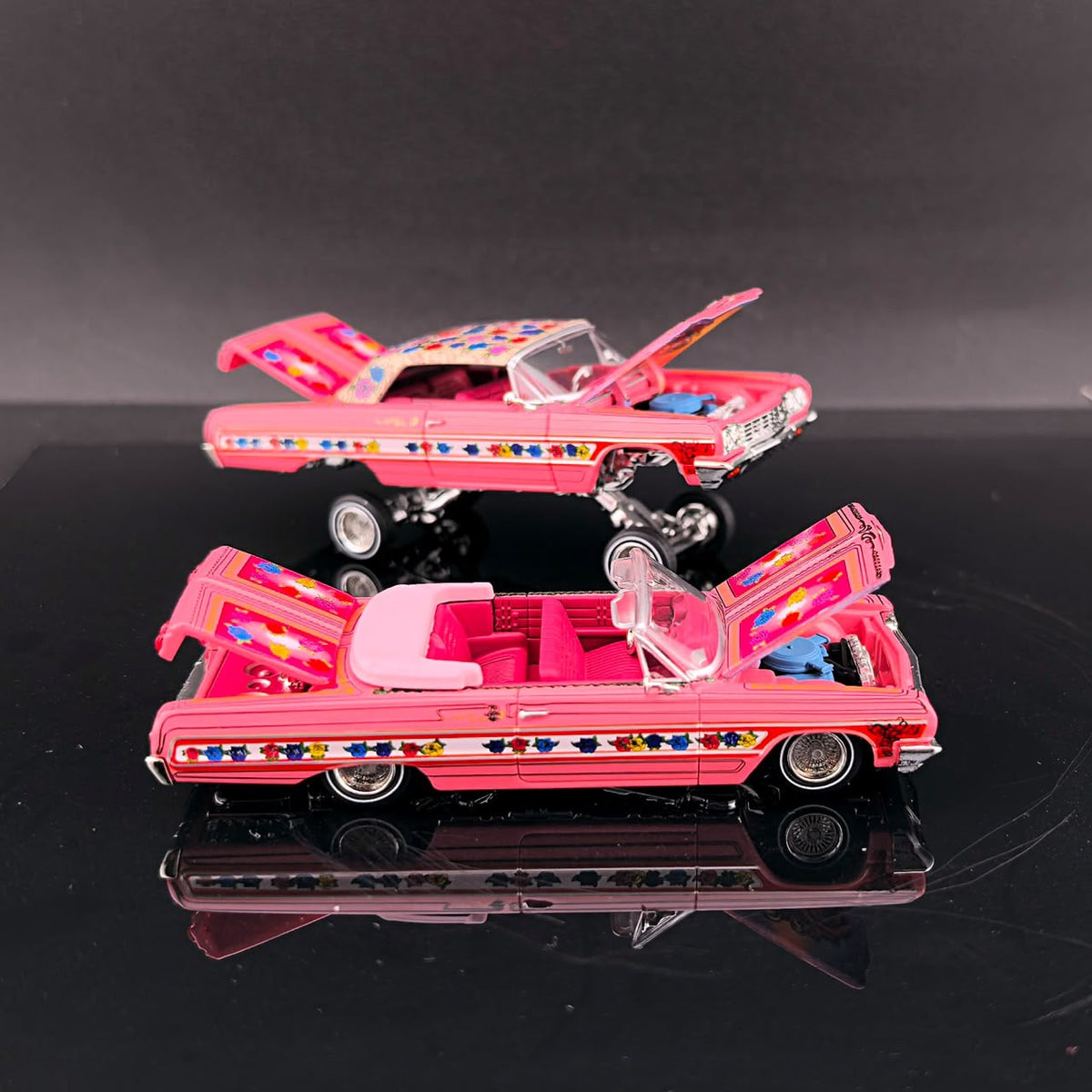 Lifted Gypsy Rose Impala with hood open above a convertible with doors open