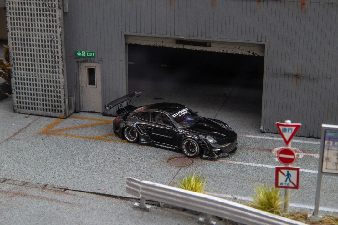 Star Models 1:64 Porsche 997 widebody in gloss black, front three-quarter from the right
