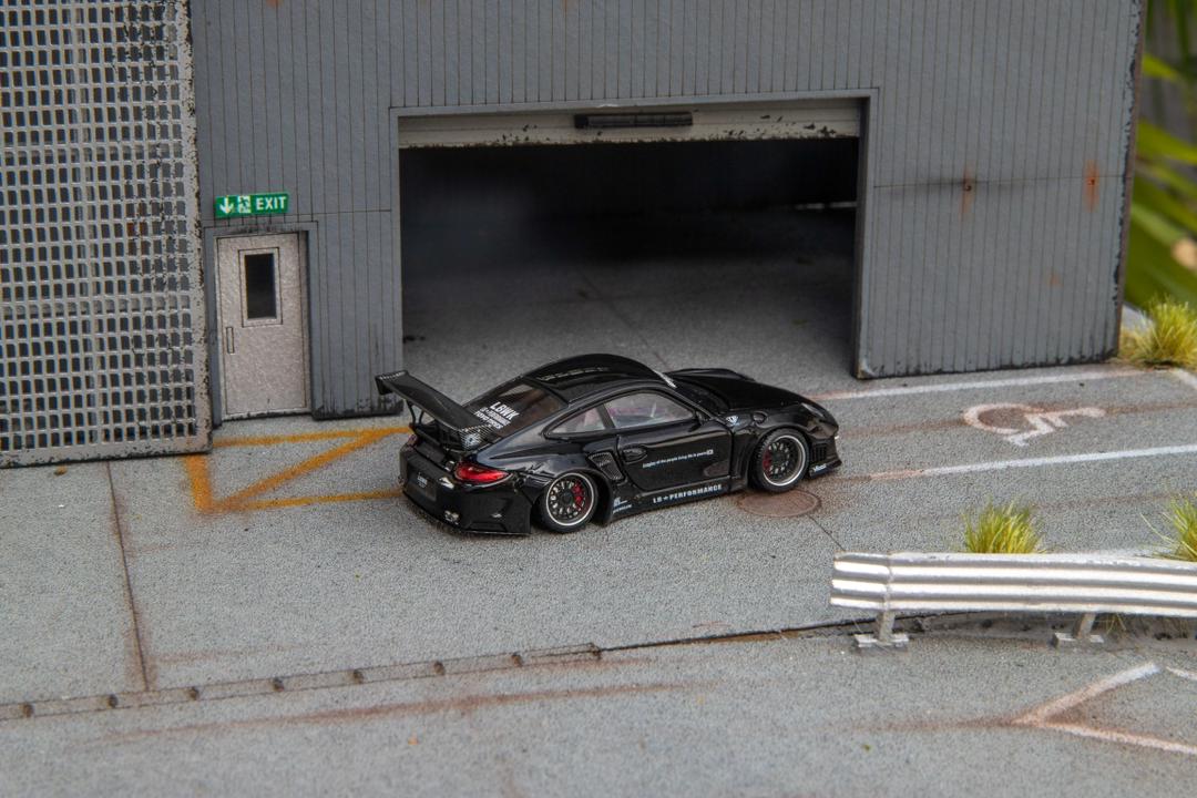Star Models 1:64 Porsche 997 widebody in gloss black, rear three-quarter showing the large rear wing
