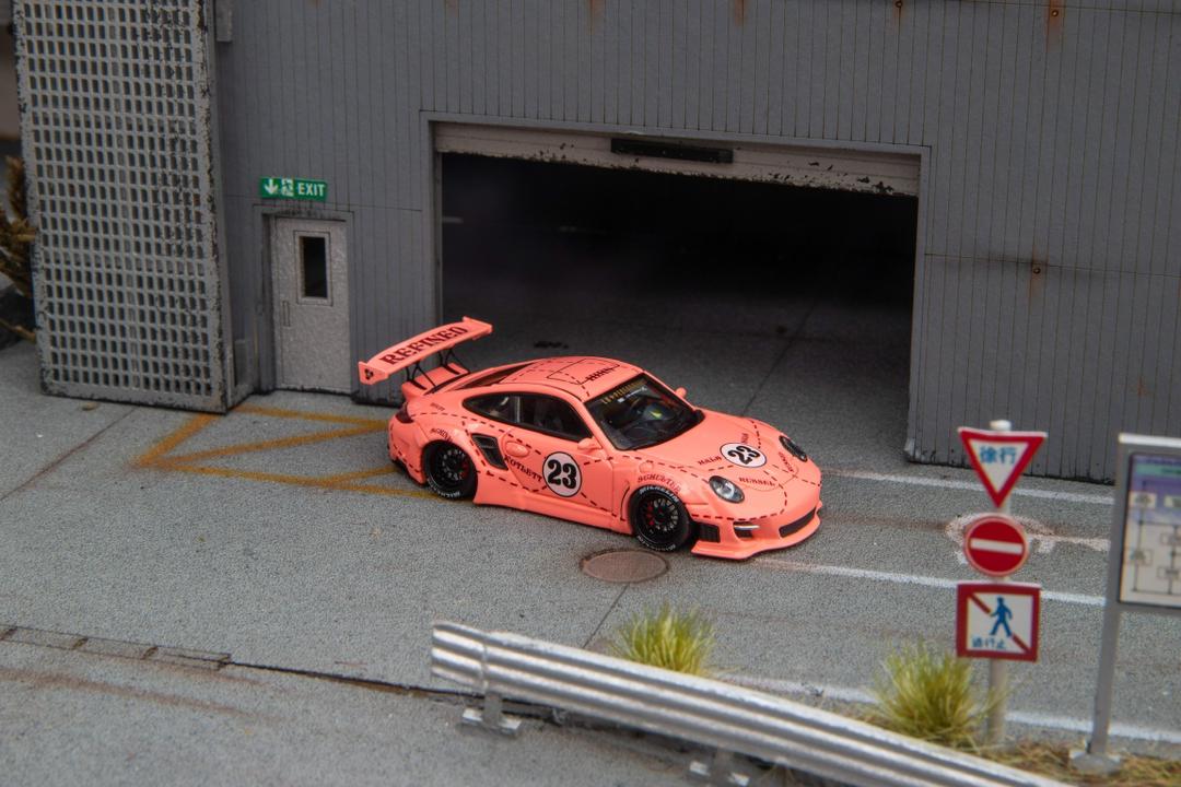Star Models 1:64 Porsche 997 widebody in Pink Pig livery with number 23 roundel, front three-quarter from the right