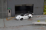 Star Models 1:64 Porsche 997 widebody in white with a carbon roof, front three-quarter view in a loading-dock diorama