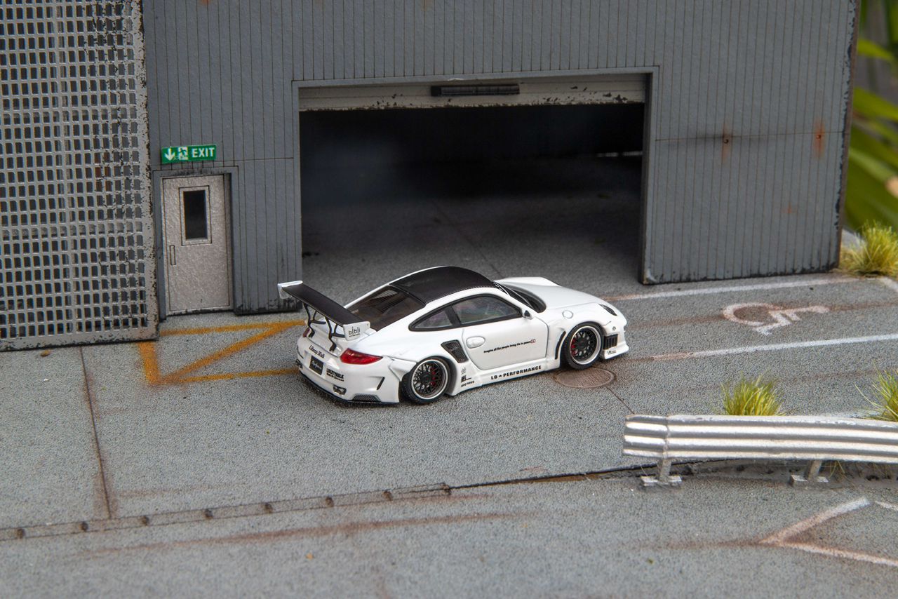 Star Models 1:64 Porsche 997 widebody in white with a carbon roof, rear three-quarter showing the large rear wing