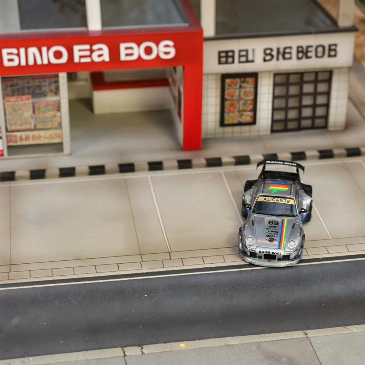 SW RWB Porsche 993 Apple Racing Livery Low Wing 1:64 diecast model, front view in a street diorama with rainbow stripe