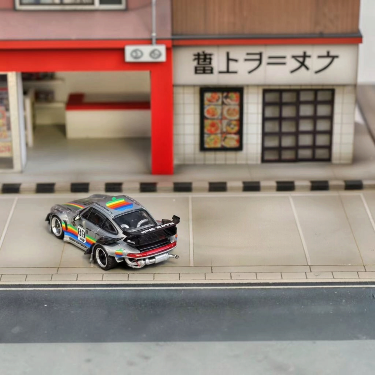 SW RWB Porsche 993 Apple Racing Livery Low Wing 1:64 diecast model, rear three-quarter in a Japanese street diorama