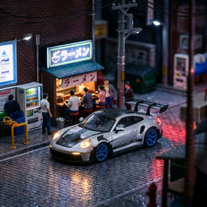 Lot57Supplies Diecast Shop 1:64 metallic silver Porsche 992 GT3 RS resin model with blue wheels and black accents.