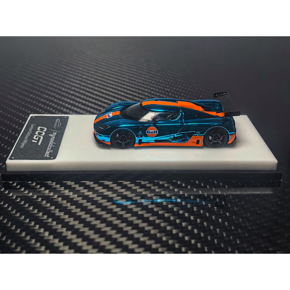 Lot57Supplies Diecast Shop 1:64 scale diecast Koenigsegg CCGT in chrome Gulf blue and orange livery on display stand