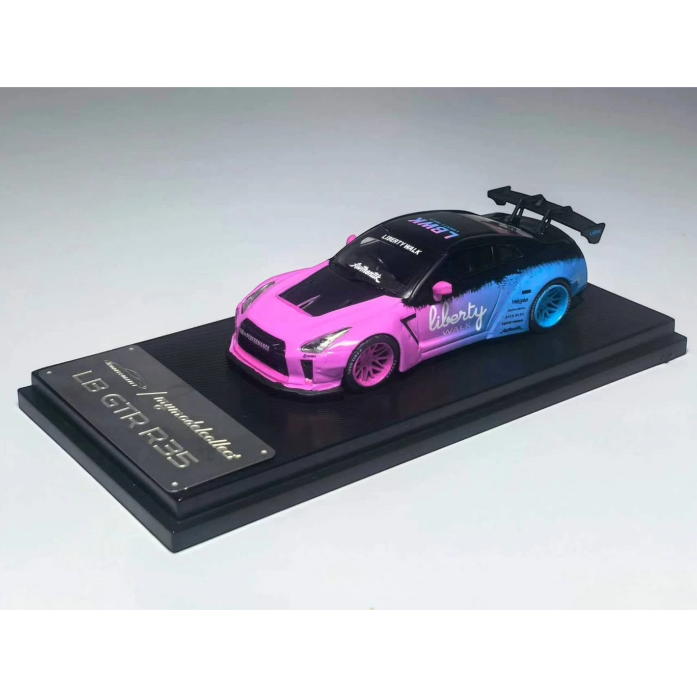 Lot57Supplies Diecast Shop 1:64 scale MC LB GTR 1.5 diecast car in flash pink and blue gradient livery on display base