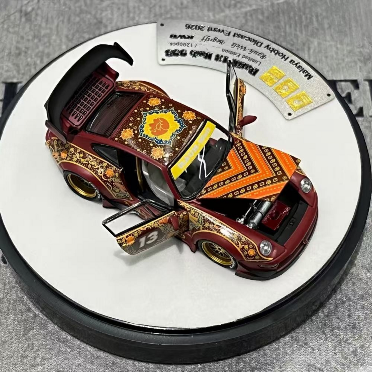 Lot57Supplies Diecast Shop PGM Porsche RWB 993 Batik 13 diecast model in red with gold alloys and intricate patterns.